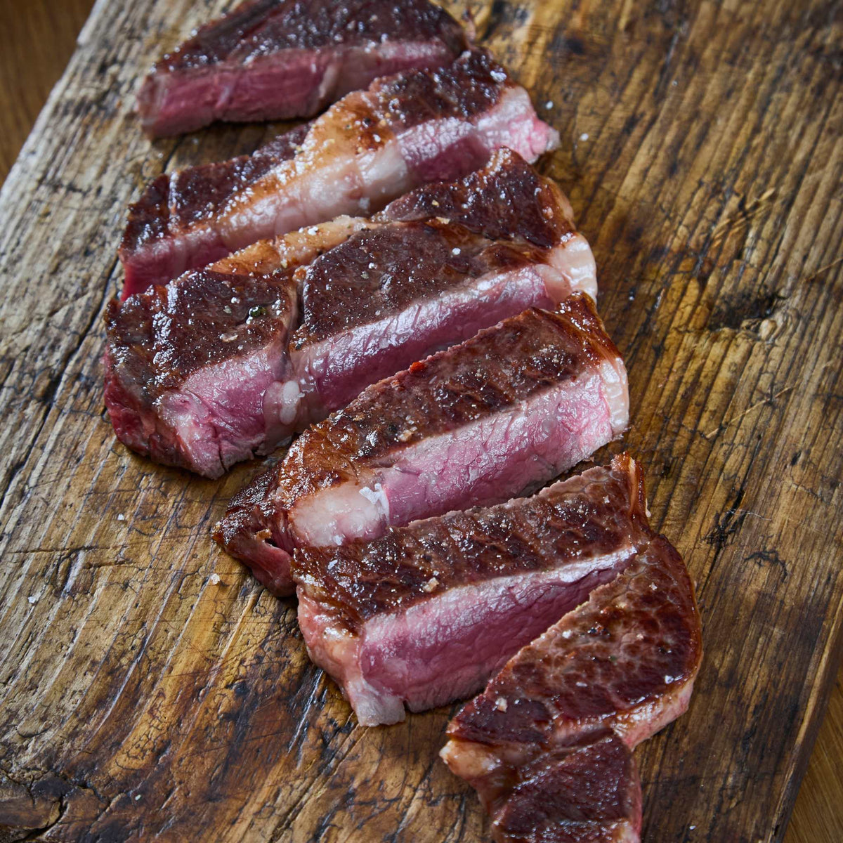 Wagyu British Beef Ribeye Steak sliced with rich marbling and a seared crust on a wooden board