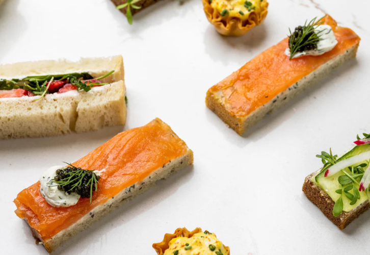 Caviar tea sandwiches with smoked salmon on rye bread topped with Royal Baeri caviar and dill cream cheese