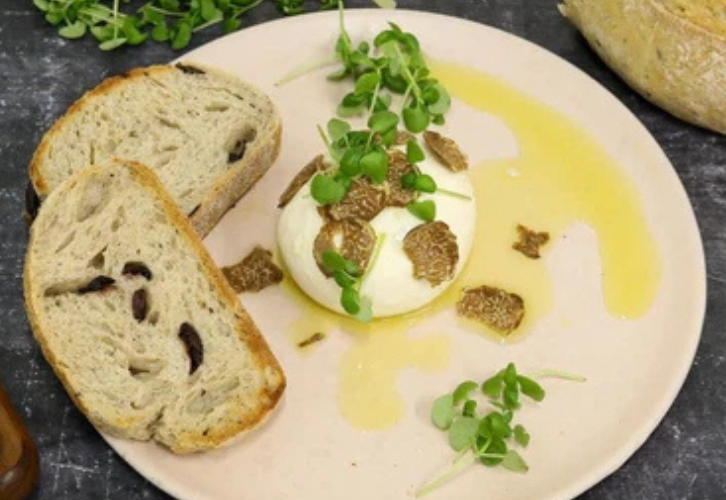 Creamy burrata topped with fresh Alba white truffle shavings and micro basil, served with olive bread