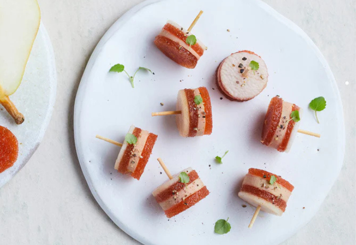 Foie gras skewers with pear and quince paste appetizer on a white plate
