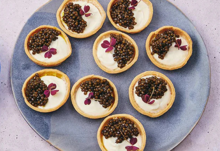 Caviar tartlets with crème fraîche and Beleaev Imperial Gold Caviar garnished with micro herbs on a serving platter