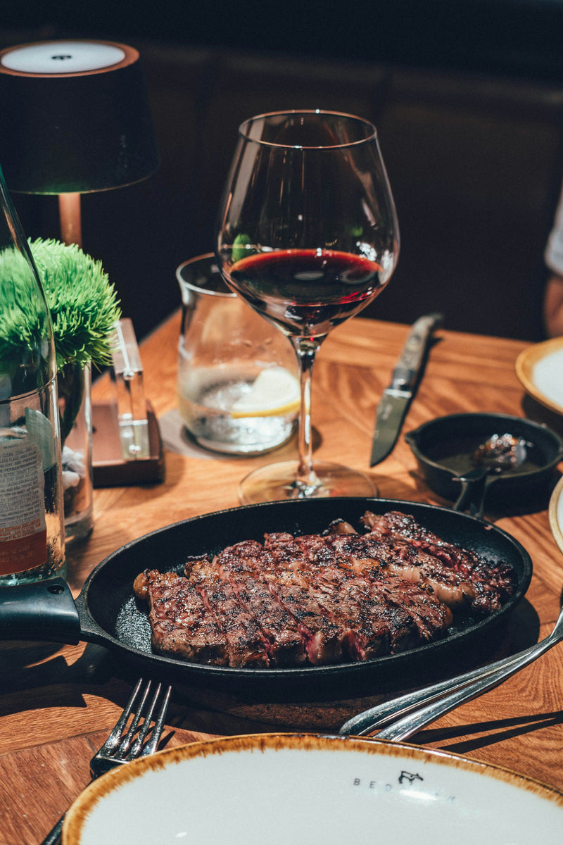 Cooked steak in a cast-iron pan with a glass of wine