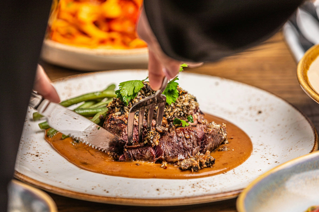 Person cutting a cooked steak on a plate; editorial image for the doneness guide