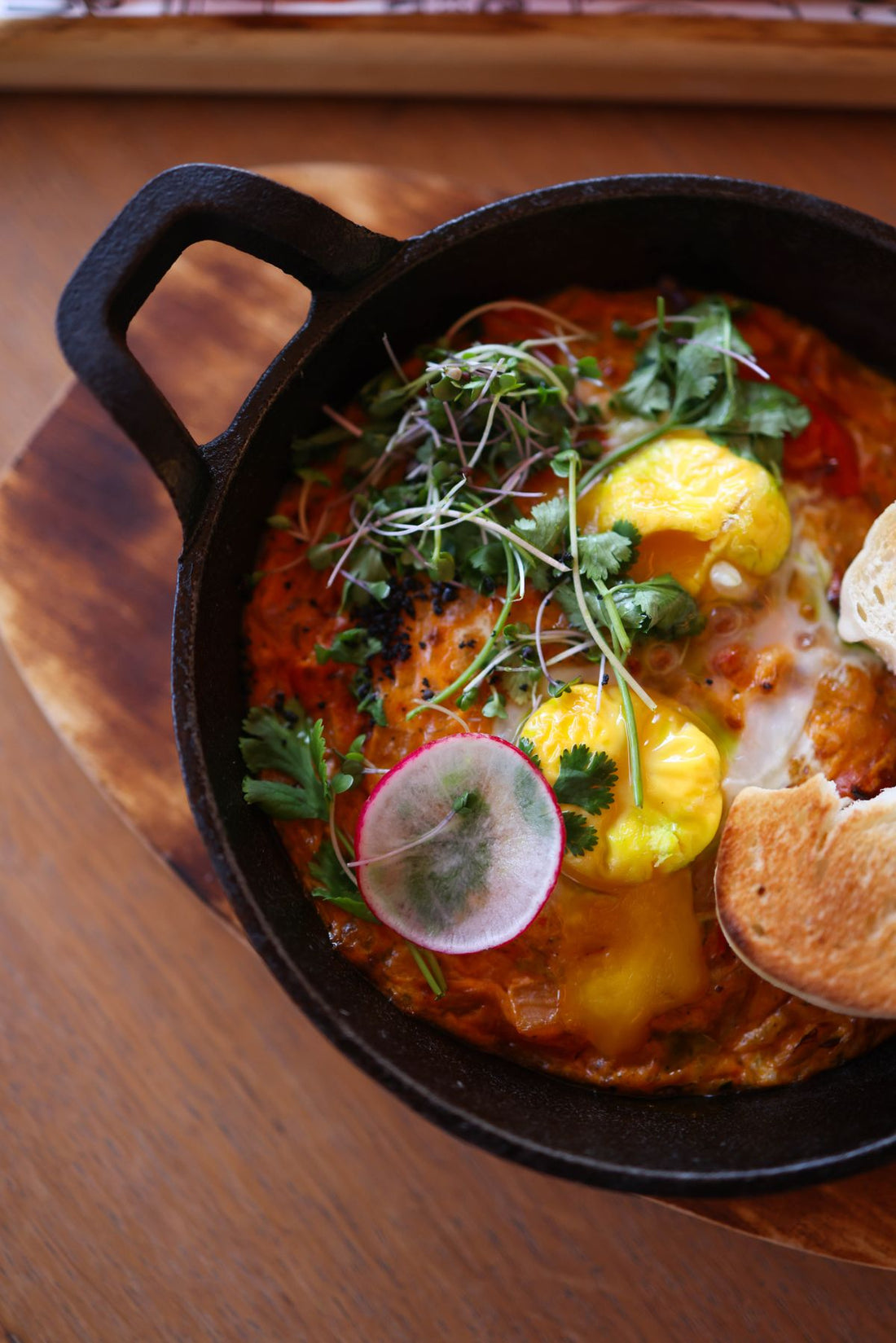 Shakshuka with poached eggs and herbs in a cast-iron pan