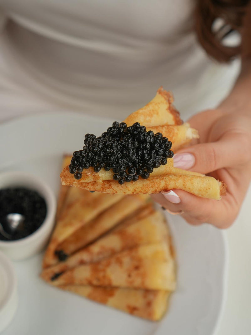Premium caviar tin served on crushed ice with mother of pearl spoons for elegant service