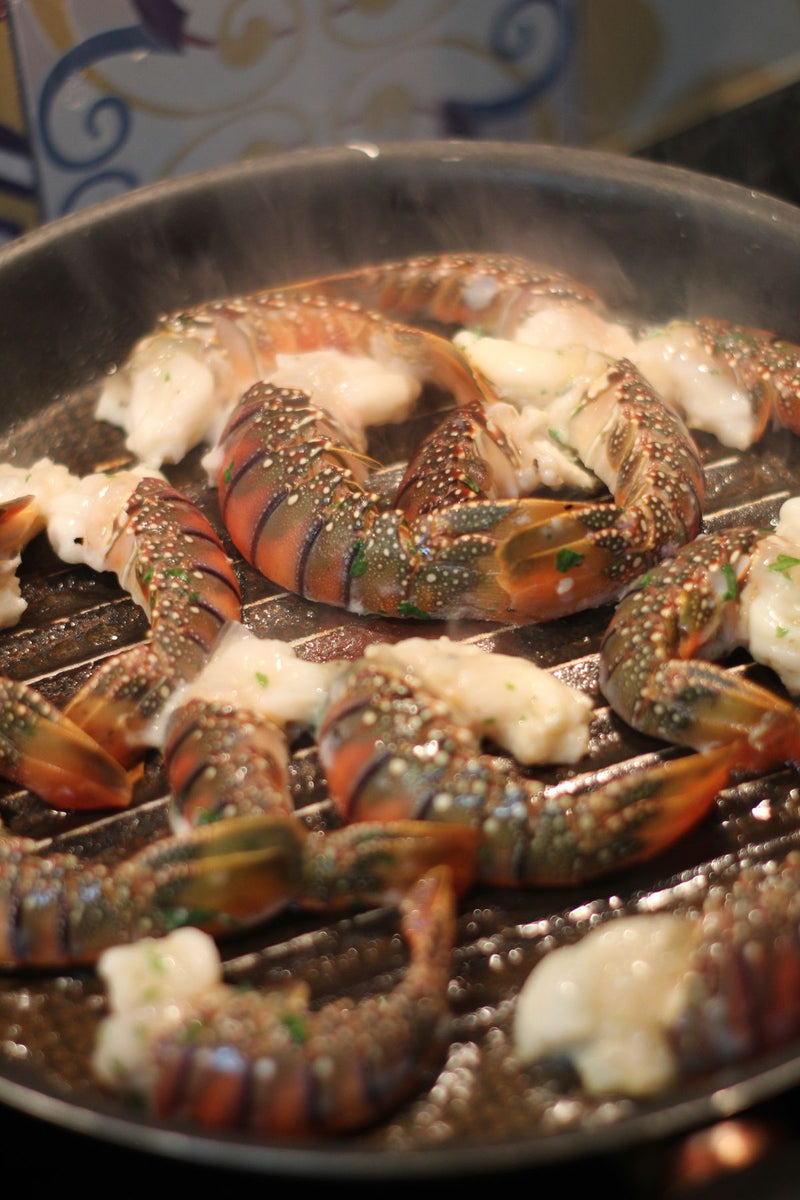 Lobster tails roasting with butter and herbs, steam rising
