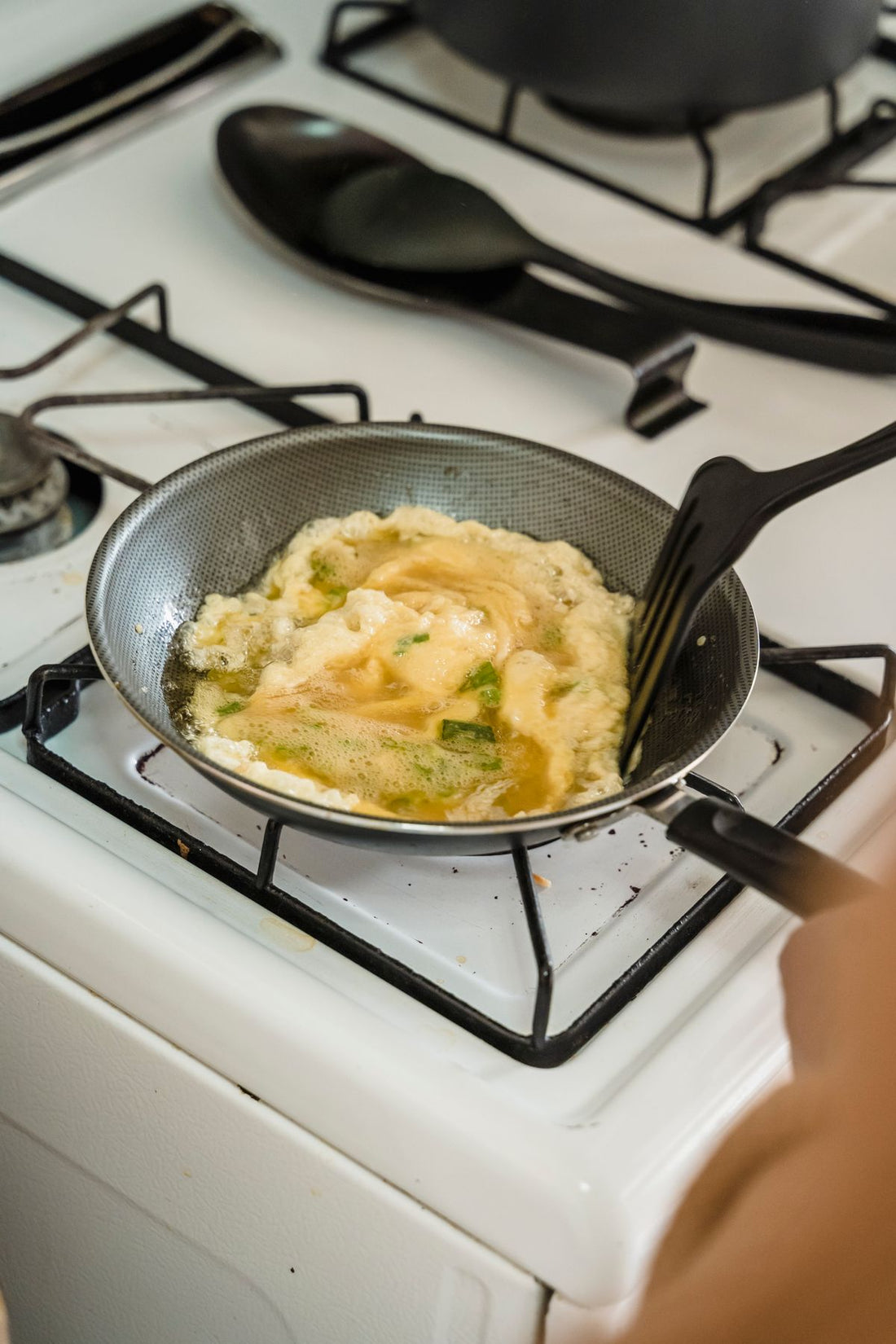 Soft scrambled eggs being folded with a spatula in the pan