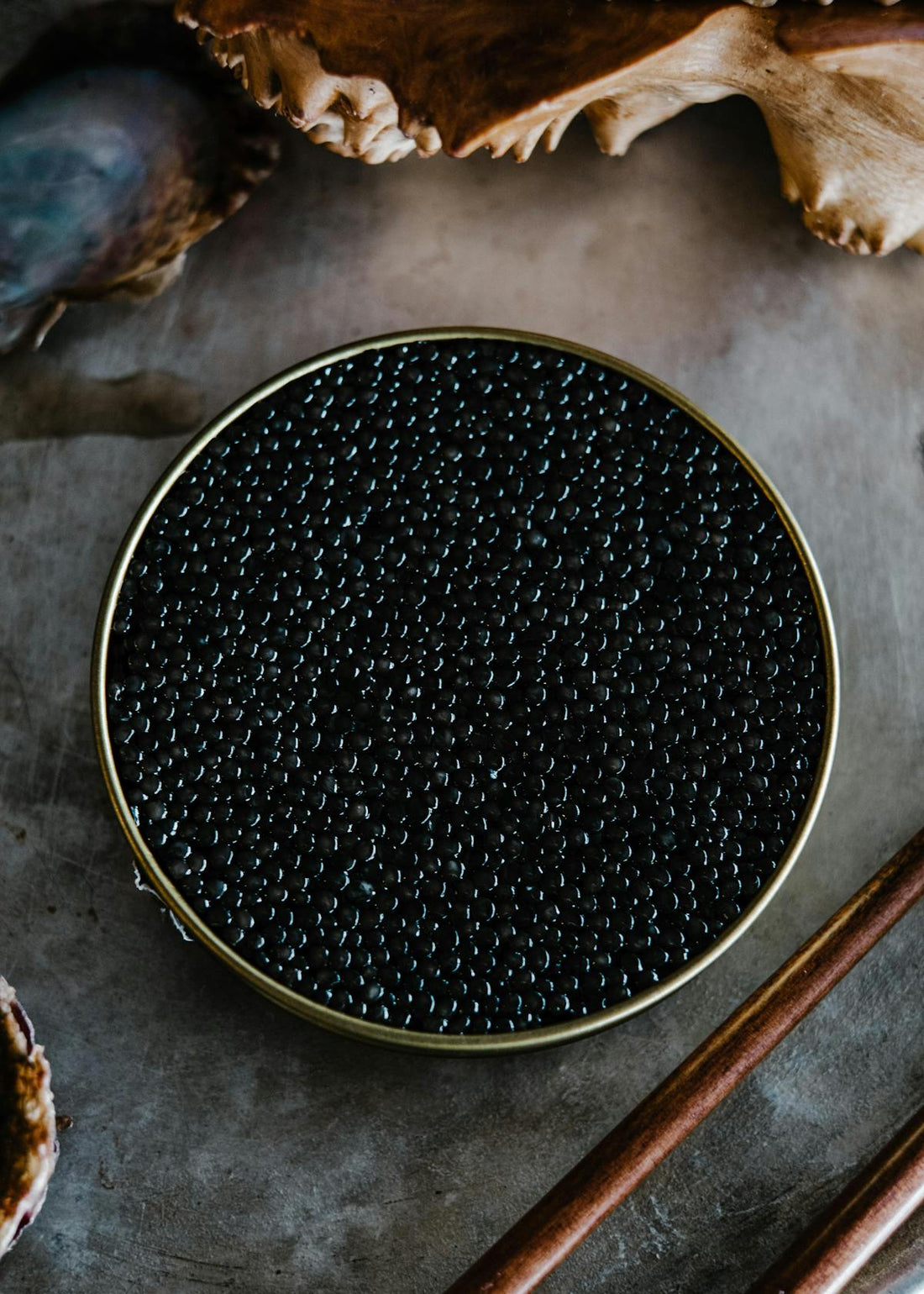 Premium caviar gift set with Oscietra and Baerii tins, mother-of-pearl spoons, and blinis on white marble background