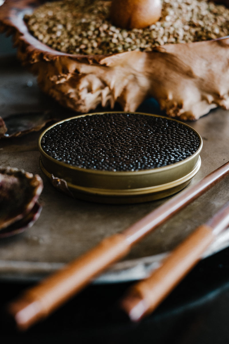 Classic caviar platter with Oscietra in tin on ice surrounded by egg yolks, egg whites, shallot, sour cream, lemon and blinis