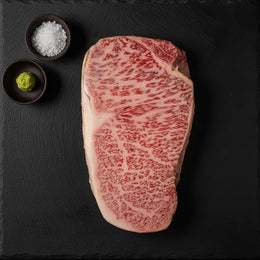 Raw Japanese A5 Wagyu sirloin steak with salt and wasabi on black slate