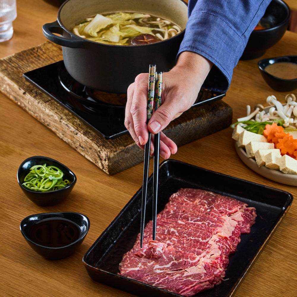 British Wagyu Beef thinly sliced marbled raw beef with chopsticks beside a Japanese hot pot