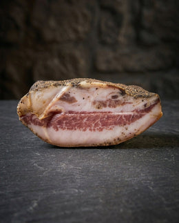 Guanciale matured pork cheek slab weighing approximately 1kg on a wooden surface