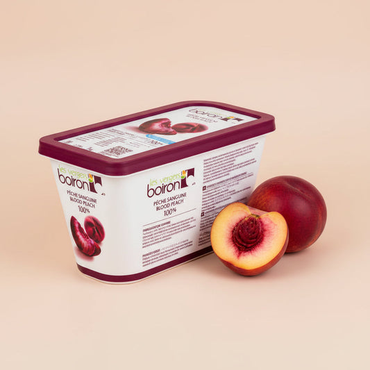 Purée Blood Peach in a white Boiron tub with a burgundy lid, shown with whole and halved red-fleshed peaches