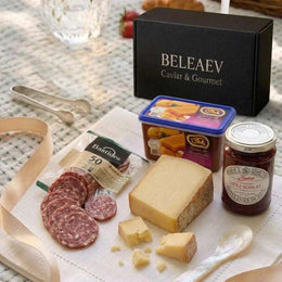 Summer Picnic Hamper with Comté, Manchego, saucisson, strawberry conserve, quince paste, and toast on a wooden board