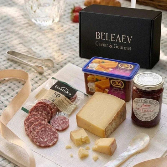 Summer Picnic Hamper with Comté, Manchego, saucisson, strawberry conserve, quince paste, and toast on a wooden board