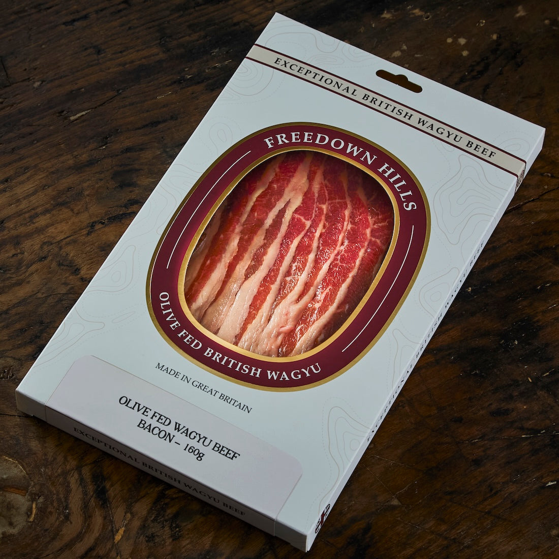 Wagyu British Beef Bacon in white and maroon packaging with visible marbled red and white bacon slices inside, olive-fed Yorkshire beef