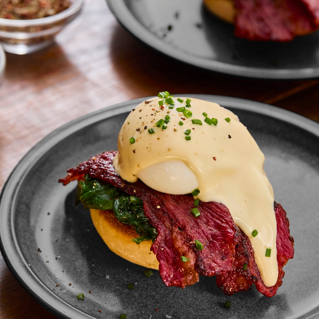 Wagyu British Beef Bacon served on a toasted bun with wilted spinach, topped with a poached egg and creamy hollandaise sauce garnished with chopped chives