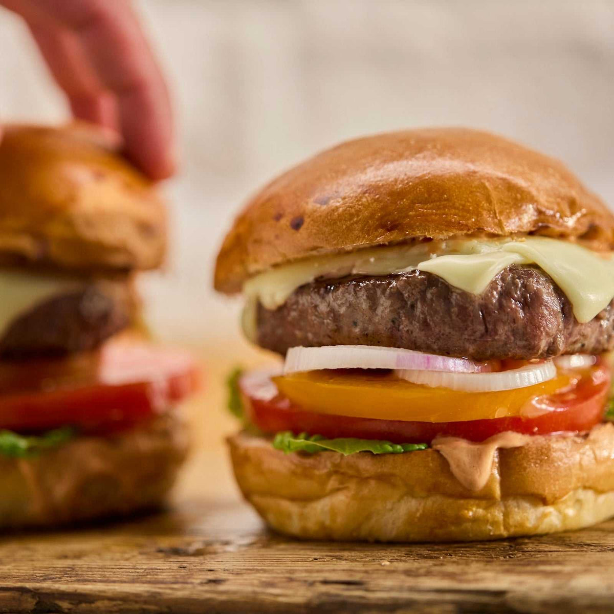 Wagyu British Beef Burgers with melted cheese, tomato, onion, lettuce, and sauce on toasted buns, showcasing juicy gourmet patties