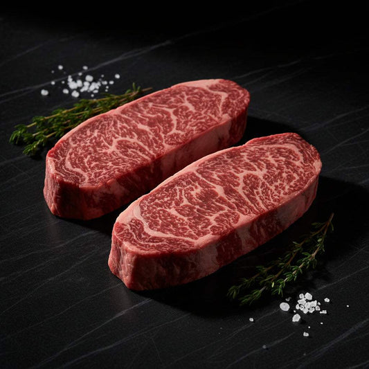 Wagyu British Beef fillet steaks with high marbling, rich red color and intricate fat marbling, presented with sprigs of herbs and salt flakes
