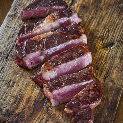 Wagyu British Beef Ribeye Steak sliced with rich marbling and a seared crust on a wooden board