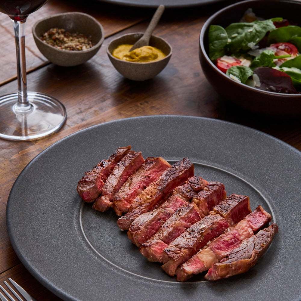 Wagyu British Beef Ribeye Steak sliced medium rare with a browned crust and pink interior served on a grey plate
